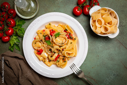 Italian pasta Calamarata made with  thick ring pasta paccheri, calamari or sliced squid, and tomato sauce.  Ingredients. Originates from Naples, the South of Italy. Directly above. photo