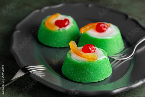 Italian dessert Cassata siciliana. Typical sicilian cheese cake made with almond, sponge cake, ricotta cheese and candied fruit, cherry and orange, with shell of green marzipan icing. Dark background.