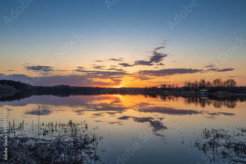 Spring landscape. Sunset on the river. Sunset sky with clouds reflected in the water.