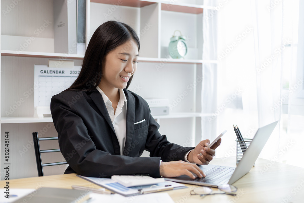 Finance workers are reviewing the company's financial data on a laptop and using smartphones to communicate or chat with the team during social distances, Talk to coworkers over the phone. Finance workers are reviewing the company's financial data on a laptop and using smartphones to communicate or chat with the team during social distances, Talk to coworkers over the phone.