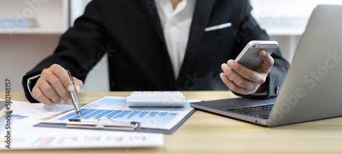 Konstfotografi Finance workers are reviewing the company's financial data on a laptop and using smartphones to communicate or chat with the team during social distances, Talk to coworkers over the phone