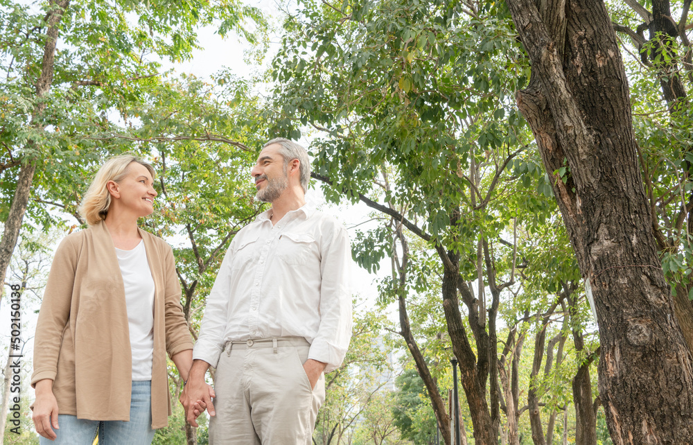 Smiling senior man and woman holding hand, talking and walking at park, Love marriage life goals, Happy retirement elder couple spending time, talking, sharing and relaxing together concept Smiling senior man and woman holding hand, talking and walking at park, Love marriage life goals, Happy retirement elder couple spending time, talking, sharing and relaxing together concept