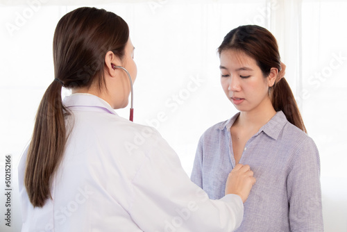 Young woman doctor in white uniform using stethoscope to check pulse female patient. Asian nurse measure heart rate by stethoscope at hospital. Medical insurance service concept.