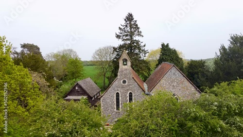 Drone ascending to reveal a church hidden behind green trees this is Blean church near Canterbury photo