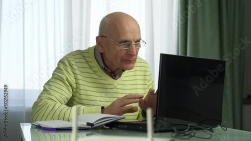 Old smart teacher wearing glasses have online lesson from home using laptop. Remote education at distance concept. photo