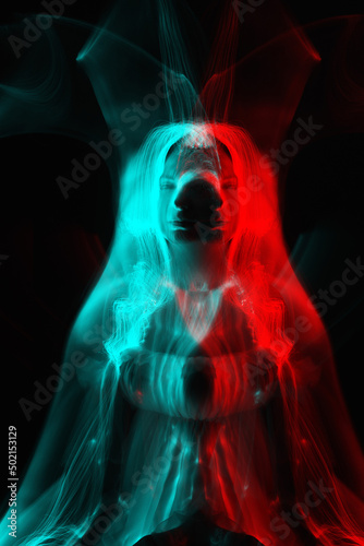 Woman silhouette in bright light trails of light painting in red and blue color channel reflection split. Portrait in style of light painting. Long exposure photo. Image contains noise and motion blur