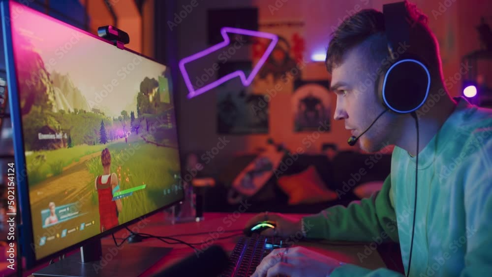 Joyful Gamer Playing PvP Shooter Video Game in Which Players Fight in a Battle Royale Deathmatch on His Personal Computer. Room and PC with Colorful Neon Led Lights. Stylish Man in Cozy Room at Home. Joyful Gamer Playing PvP Shooter Video Game in Which Players Fight in a Battle Royale Deathmatch on His Personal Computer. Room and PC with Colorful Neon Led Lights. Stylish Man in Cozy Room at Home.