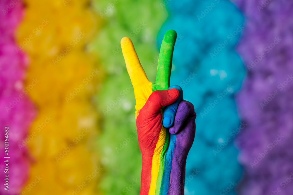 Rainbow colors painted hand making peace sign. Rainbow colors background. Gay pride symbol. 