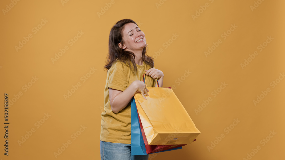 Smiling woman holding shopping bags feeling ecstatic and pleased with purchase doing thumb up hand gesture in studio. Person feeling proud of aquisition showing excitement for buying products. Smiling woman holding shopping bags feeling ecstatic and pleased with purchase doing thumb up hand gesture in studio. Person feeling proud of aquisition showing excitement for buying products.