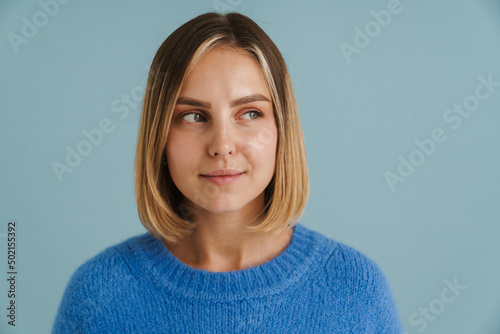 Young blonde woman wearing sweater posing and looking aside