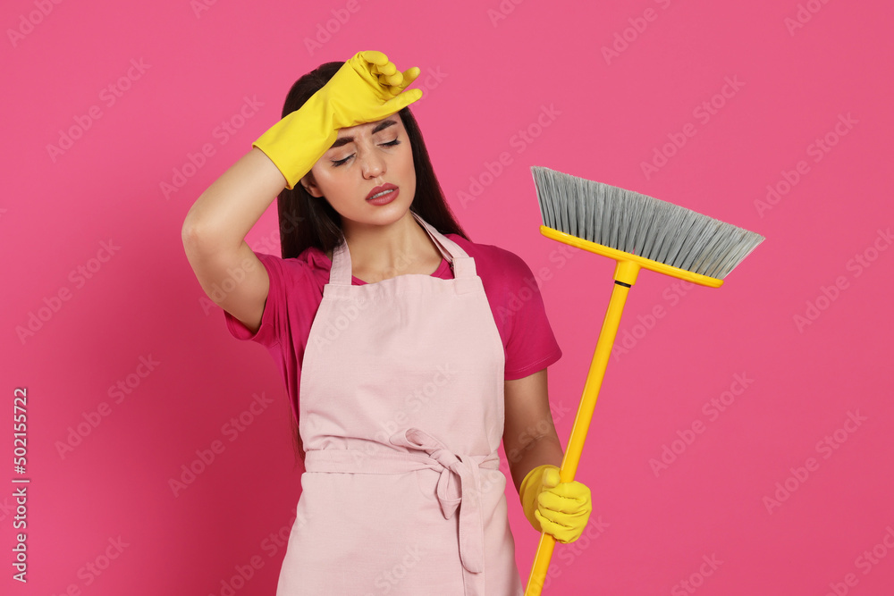 Tired young woman with broom on pink background Tired young woman with broom on pink background