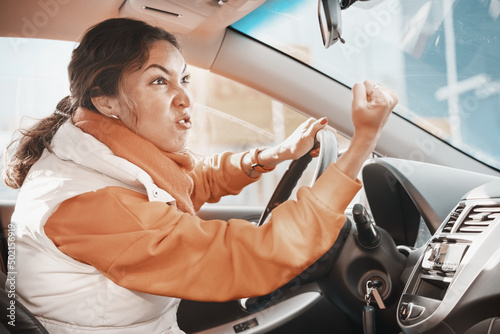 Aggressive female driver swears and shouts and gestures at other road users who violate traffic rules. Concept of anger and emotion management photo