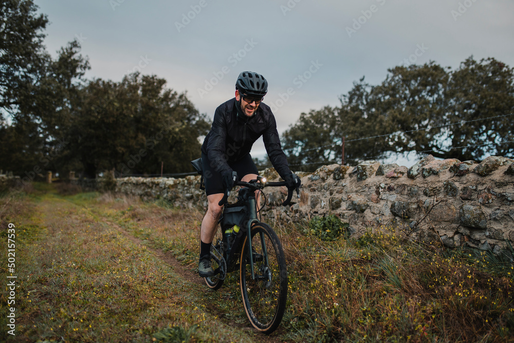 Smiling cyclist riding bicycle by wall Smiling cyclist riding bicycle by wall