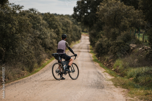 Cyclist with bicycle standing on gravel road photo