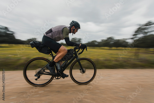 Blurred motion of cyclist cycling on dirt road photo