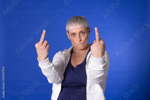 Angry woman showing obscene gesture against blue background