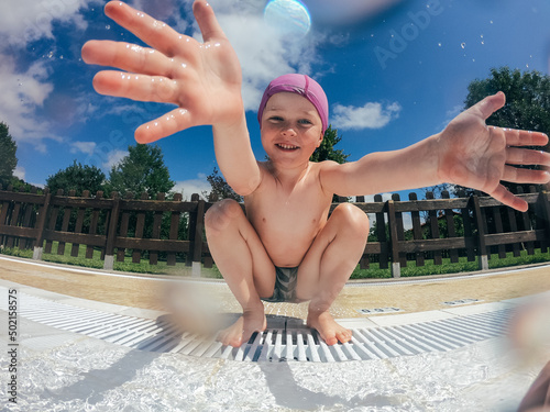 child throws water on the camera in the swimming pool