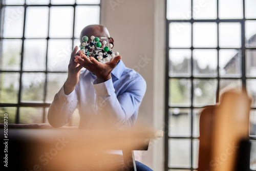 Scientist holding molecular structure at desk in home