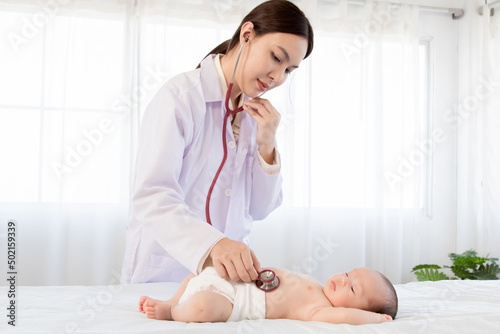 Beautiful doctor hand using stethoscope examining adorable infant heart, asian newborn baby get sick sleep during examine by pediatrician hand hold stethoscope in clinic.