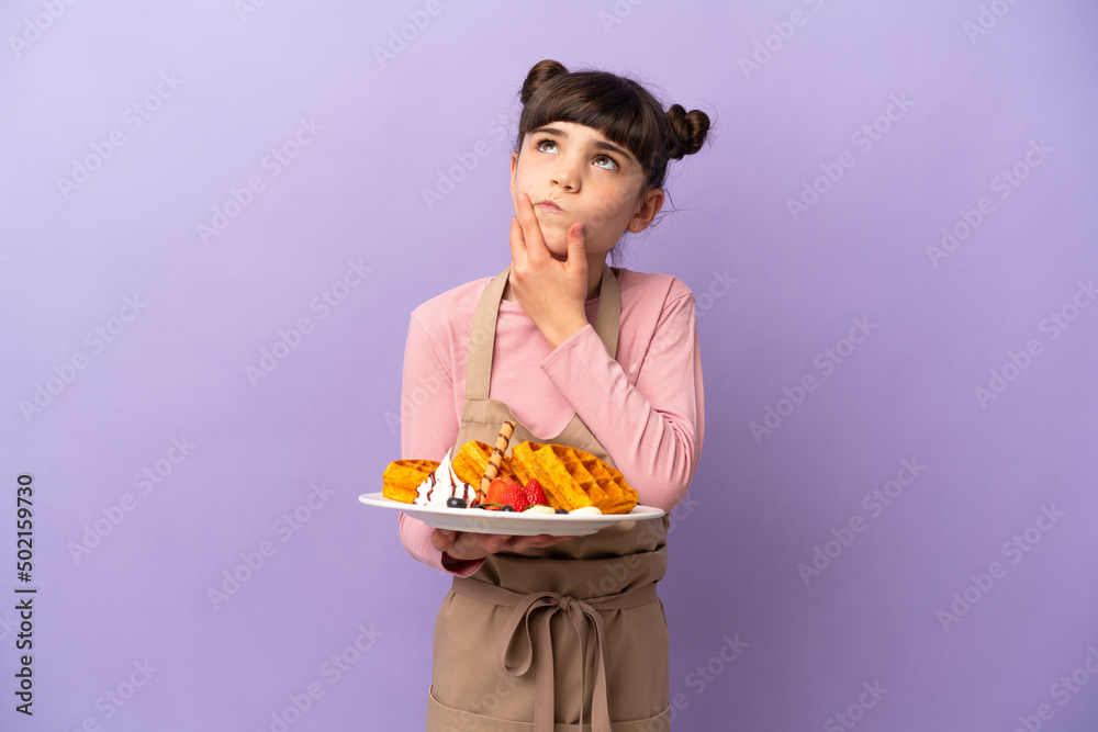 Little caucasian girl holding waffles isolated on purple background having doubts Little caucasian girl holding waffles isolated on purple background having doubts