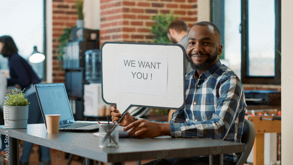 Portrait of african american man showing speech bubble with hiring offer, advertising recruitment meeting. Male worker holding text message on board to create work employment ad. Portrait of african american man showing speech bubble with hiring offer, advertising recruitment meeting. Male worker holding text message on board to create work employment ad.