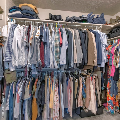 Square Full walk in closet with clothes hanging on the clothing rods