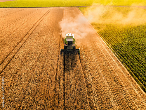 Combine harvester with smoke at farm on sunny day photo