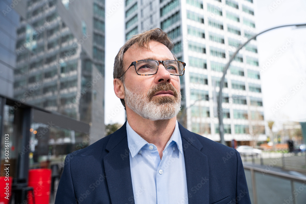 Businessman with eyeglasses contemplating near building Businessman with eyeglasses contemplating near building