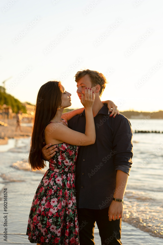 Young woman embracing boyfriend at beach of sea on sunny day