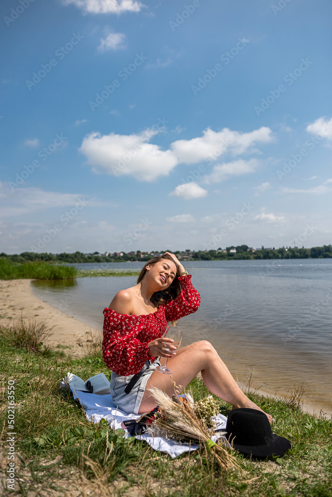 Young woman alone sits near lake at summer day Young woman alone sits near lake at summer day