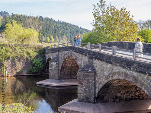 three people  walking across a three arch medieval stone bridge in the United Kingdom photo