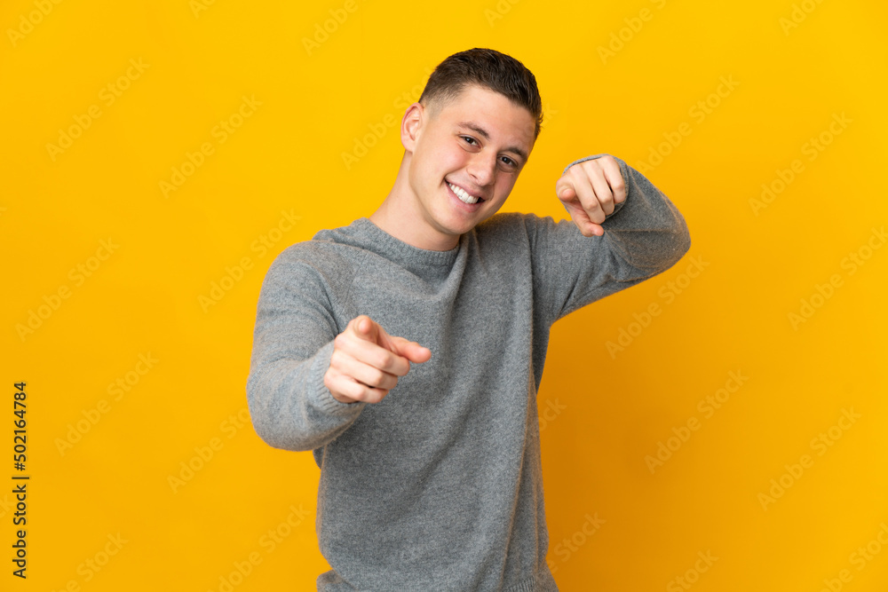 Young caucasian man isolated on yellow background pointing front with happy expression Young caucasian man isolated on yellow background pointing front with happy expression
