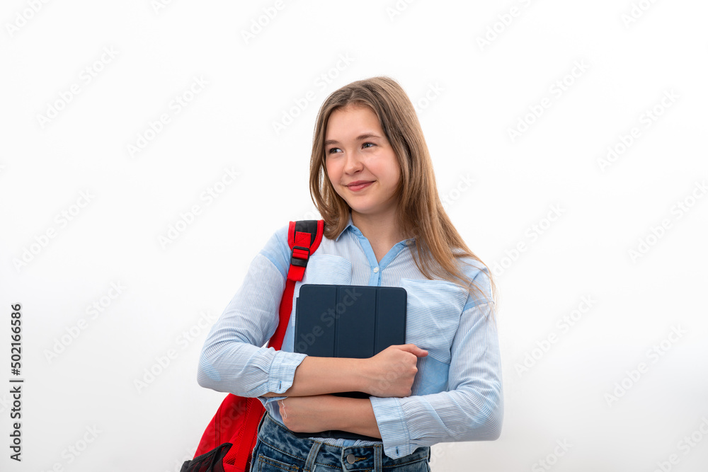 Teenager girl stands with a backpack and a tablet in her hands against white background in studio Teenager girl stands with a backpack and a tablet in her hands against white background in studio