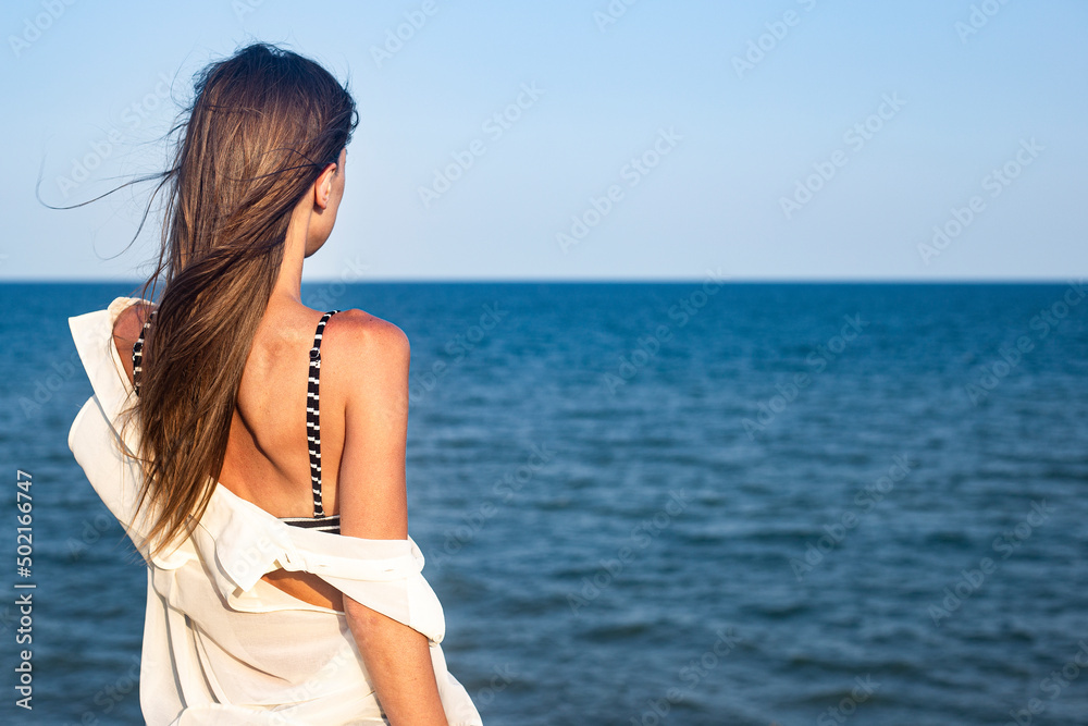 Beautiful sexy young woman in a light pareo on a cliff looks at the sea. Beautiful sexy young woman in a light pareo on a cliff looks at the sea.