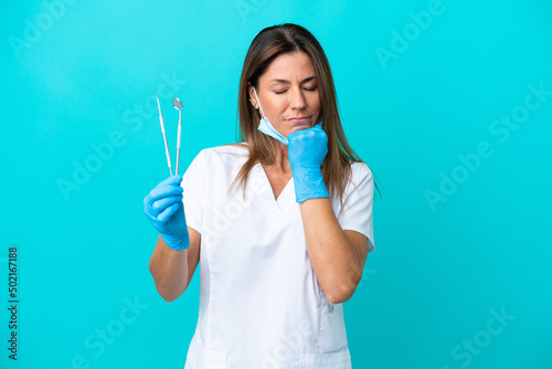 Middle age doctor woman isolated on blue background having doubts