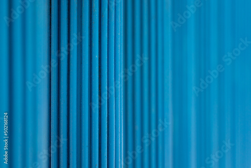 Abstract background with blue vertical pipes. Selective focus