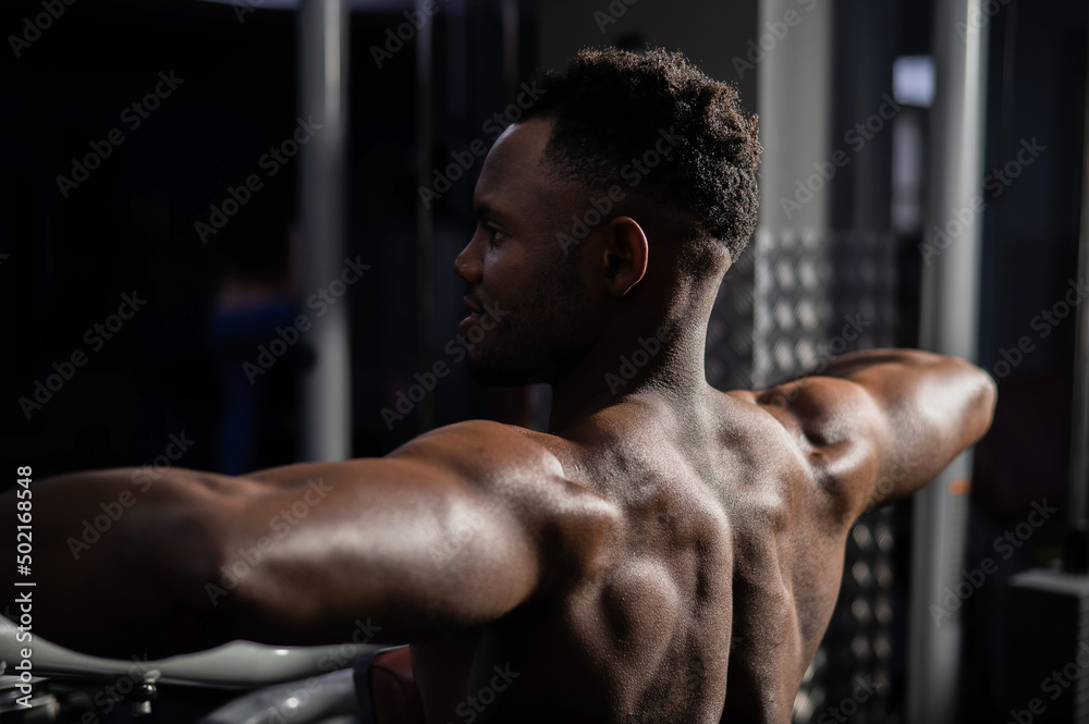 Shirtless african american man doing back exercises on a machine in the gym. Shirtless african american man doing back exercises on a machine in the gym.