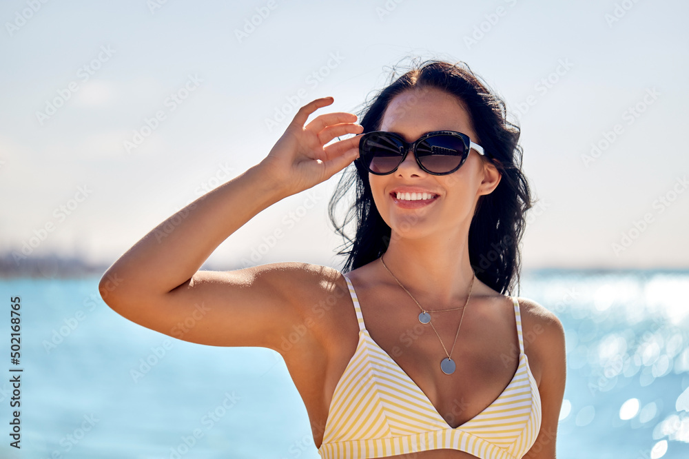 people, summer and swimwear concept - happy smiling young woman in sunglasses and bikini swimsuit on beach people, summer and swimwear concept - happy smiling young woman in sunglasses and bikini swimsuit on beach