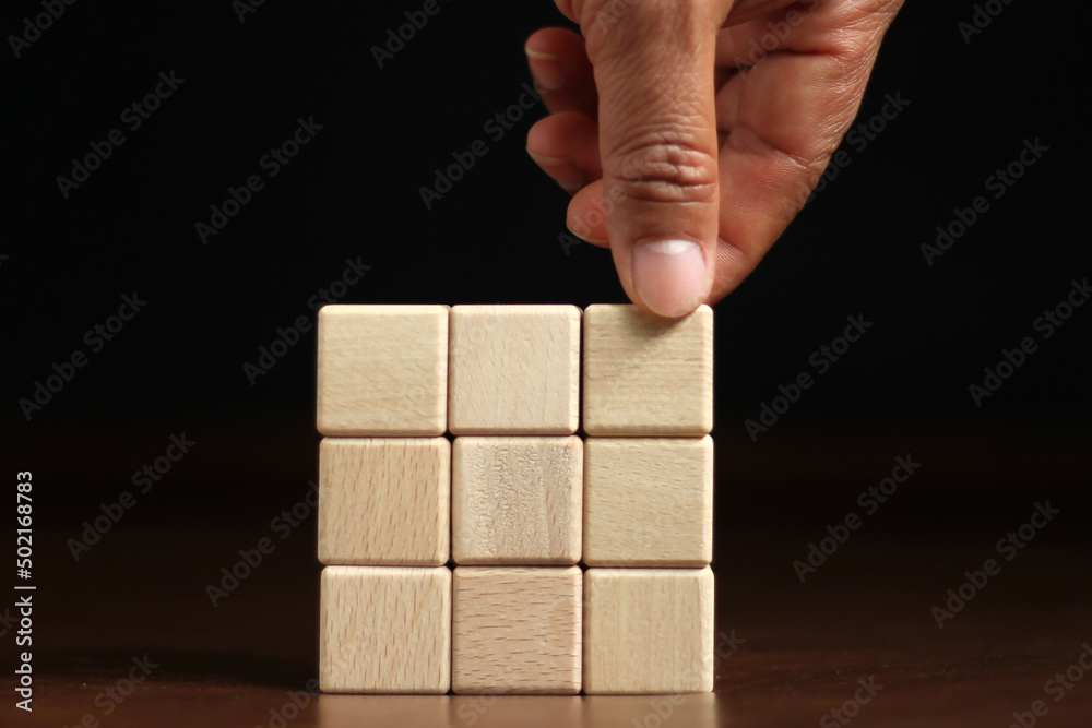 The hand picked up several empty wooden blocks stacked on top of each other. For text area, copy area The hand picked up several empty wooden blocks stacked on top of each other. For text area, copy area