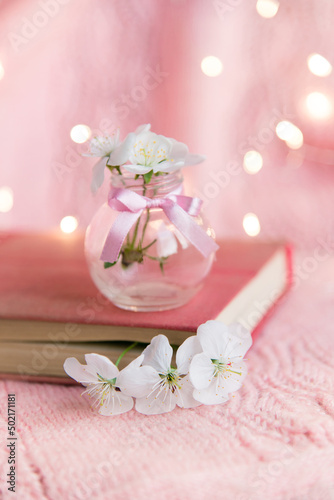 old book with white small flowers on a pink openwork background close-up.