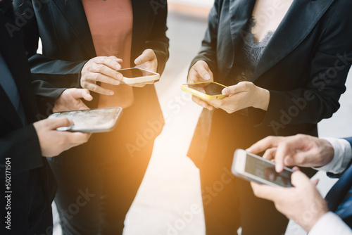A Group of young businesspeople standing and using smartphones together concepts communication. 