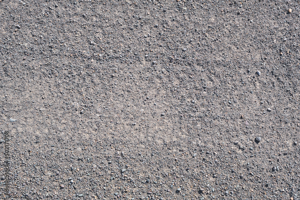 A flat area of ground covered with small stones. Fragment of the road, background. A flat area of ground covered with small stones. Fragment of the road, background.