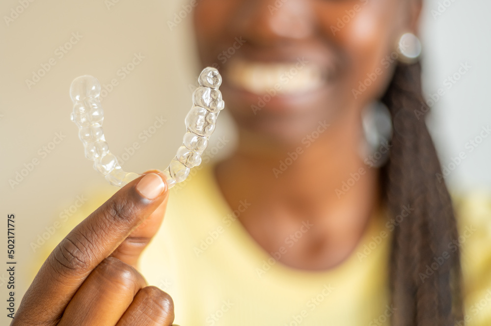 Young woman holding a invisible aligner while smiling