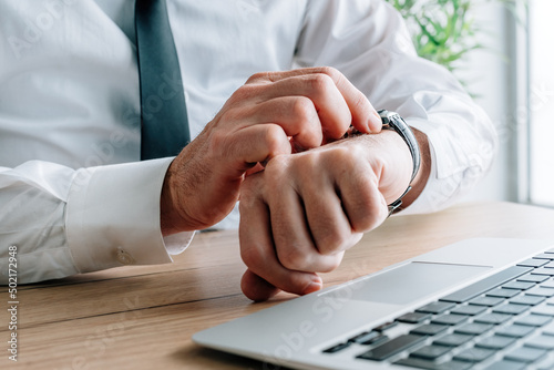 Foto Businessman late for meeting checking time on his watch in business office