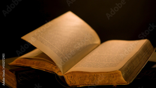 Pages of old book are turned over on isolated background. Stock footage. Ancient book with old yellow pages and patterns flipping over dark background