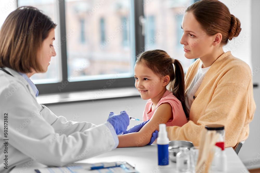 medicine, healthcare and pediatry concept - female doctor or pediatrician with syringe making vaccine injection to little girl patient at clinic medicine, healthcare and pediatry concept - female doctor or pediatrician with syringe making vaccine injection to little girl patient at clinic