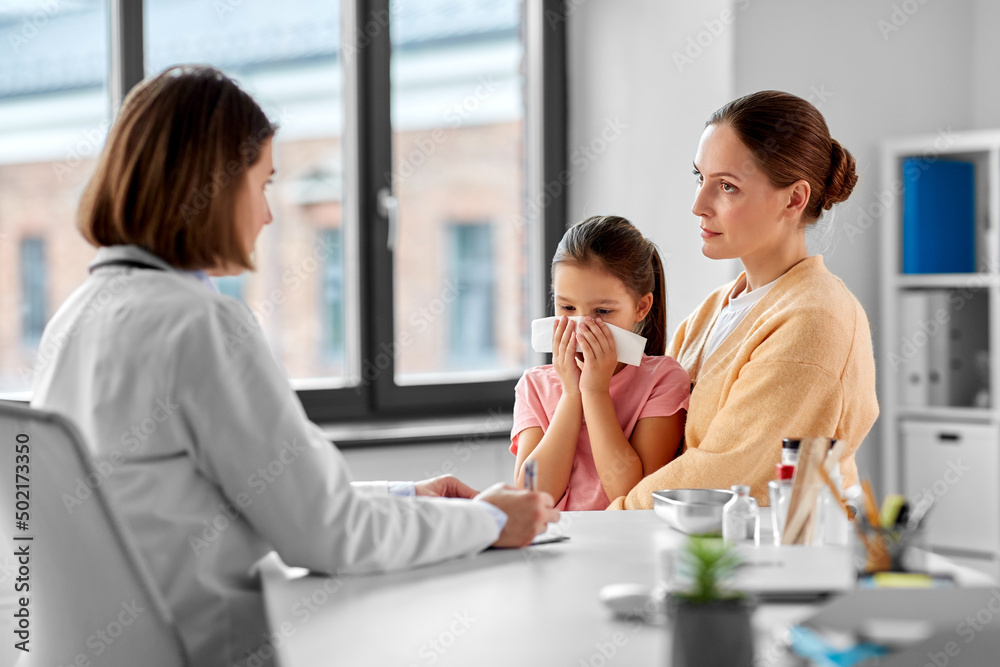 medicine, healthcare and pediatry concept - mother with little daughter blowing his nose and doctor with laptop computer at clinic medicine, healthcare and pediatry concept - mother with little daughter blowing his nose and doctor with laptop computer at clinic