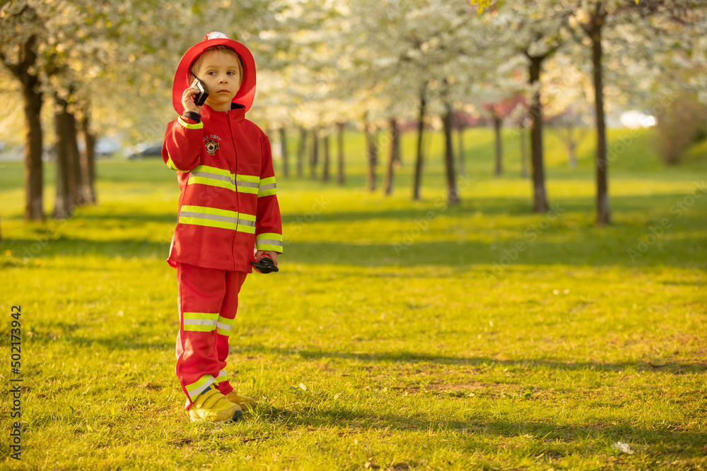 Little toddler child with fireman costume in park, pretending to be real fireman, playing Little toddler child with fireman costume in park, pretending to be real fireman, playing
