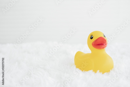 Portrait of yellow rubber duck with orange beak on white fluffy carpet. White background. Copy space