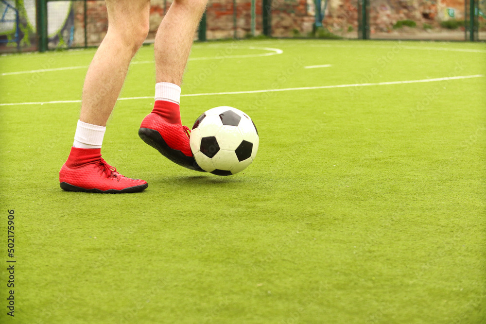 Players play mini football on the field. Legs, sneakers and a ball. Green football field. Players play mini football on the field. Legs, sneakers and a ball. Green football field.